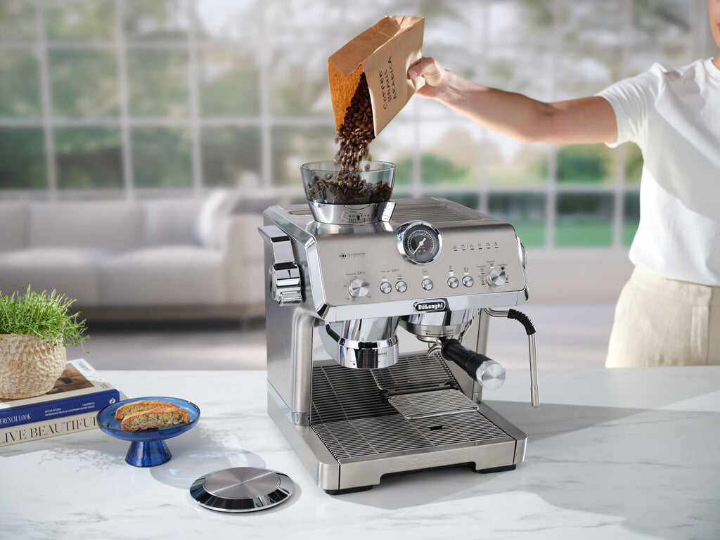 Grains de café versés dans le broyeur d'une machine expresso De'Longhi La Specialista